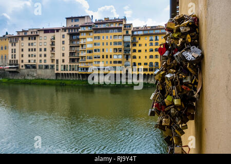 Vista sulle facciate delle case attraverso il fiume Arno, amore blocca legata al Ponte Vecchio Foto Stock