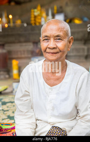 Siem Reap, Angkor, Tempel Baphuon, eine Frau die vor einer großen Buddhastatue sitzt und für Touristen gegen Geld betet Foto Stock