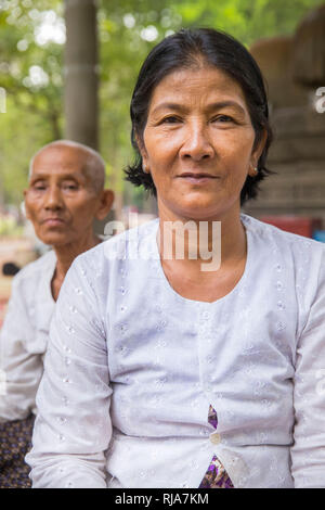 Siem Reap, Angkor, Tempel Baphuon, eine Frau die vor einer großen Buddhastatue sitzt und für Touristen gegen Geld betet Foto Stock