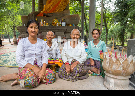 Siem Reap, Angkor, Tempel Baphuon, Betfrauen die um eine Buddhastatue herum sitzen und für Touristen gegen Geld Beten Foto Stock