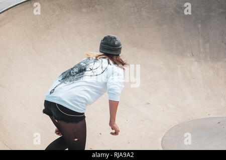 Una ragazza adolescente pattinaggio a livello Skatepark in Brighton, East Sussex, Inghilterra. Foto Stock