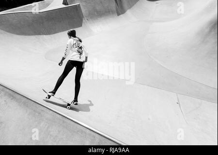 Una ragazza adolescente pattinaggio a livello Skatepark in Brighton, East Sussex, Inghilterra. Foto Stock