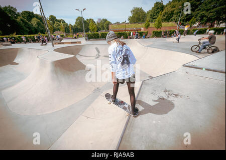 Una ragazza adolescente si prepara a pattino verso il basso una rampa a livello Skatepark in Brighton, East Sussex, Inghilterra. Foto Stock