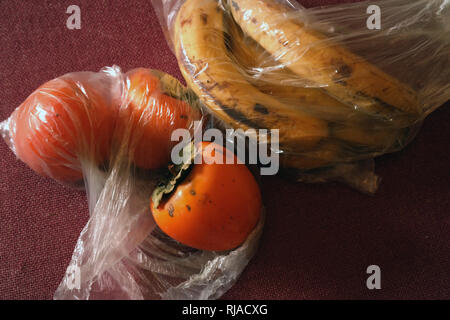 Persimmon banana e confezionati in sacchetti di cellophane, studio closeup Foto Stock