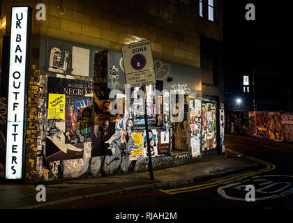 Parete ricoperta con volare poster city night scene di strada ,Commercial St, London E1 6NU Foto Stock