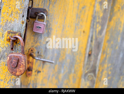 Primo piano della vecchia serratura su giallo weathered porta in legno Foto Stock