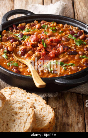 Cowboy stufato di fagioli con carne di manzo macinata, il bacon in una salsa piccante di close-up in una ciotola sul piano verticale. Foto Stock