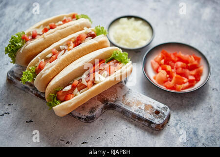 Tre barbecue grigliate di hot dog con salsiccia immessi sul tagliere di legno Foto Stock