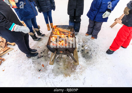 Le persone in fase di riscaldamento intorno al fuoco all'aperto pit, Winnipeg, Manitoba, Canada. Foto Stock