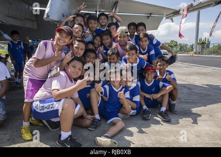 Bambini indonesiano posano per una foto a U.S. Marine Corps F/A-18D Hornet visualizzazione statica all'Aeroporto Internazionale di Ratulangi, Indonesia, nov. 5, 2016. L'evento offerto alla comunità locale la possibilità di scattare foto con i membri del servizio e visualizzare U.S. Marine Corps F/A-18D i calabroni, aeronautica militare indonesiana F-16 Fighting Falcons e l'aeronautica militare indonesiana NAS-332L1 Super Puma elicottero. Foto Stock