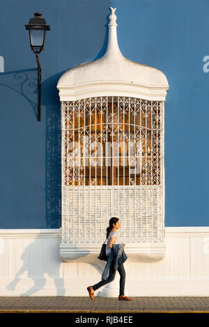 Donna passando lo stile coloniale finestra della piazza principale di Trujillo, Perú Foto Stock