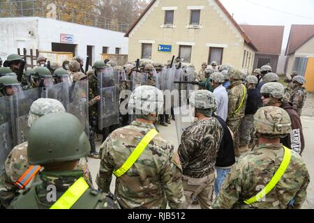 Soldati rumeni di 265Polizia Militare Battaglione e soldati armena della terza compagnia di fanteria, 2° battaglione di fanteria preparare per impegnare U.S. I soldati del primo battaglione, 4° Reggimento di Fanteria role-playing ostile civili durante la conduzione di una folla antisommossa scenario durante una forza per il Kosovo (KFOR) Missione prove generali di esercizio (MRE) al giunto multinazionale Centro Readiness in Hohenfels, Germania, nov. 4, 2016. La KFOR MRE 22 è progettato per preparare il trentasettesimo della brigata di fanteria combattere Team per il sostegno della pace e della stabilità e del contingente della cooperazione in Kosovo a sostegno delle autorità civili in ma Foto Stock