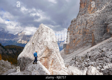 Il camminatore femmina in piedi accanto a un enorme masso in Val de Formin, nei pressi della Croda da Lago, Dolomiti, Belluno, Veneto, Italia Foto Stock