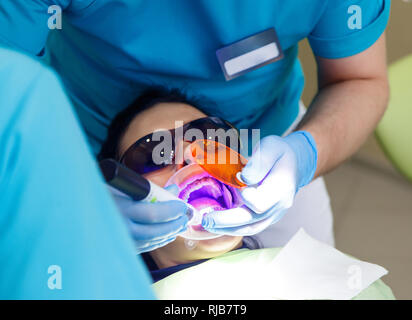 Sorridente Pretty Woman è avente i suoi denti esaminati dal dentista in clinica. Concetto di trattamento della carie Foto Stock