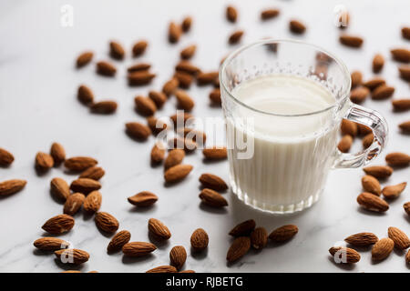 Latte di mandorle in un vetro circondato da mandorle organico Foto Stock