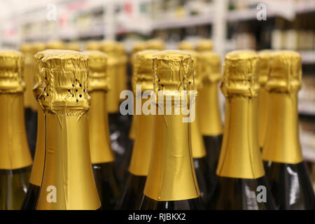 Le bottiglie di champagne in una riga, il fuoco selettivo. Produzione di vini spumanti concetto, negozio di liquori Foto Stock