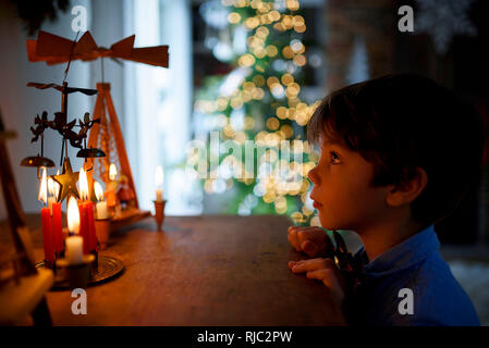 Ragazzo in piedi di fronte ad una credenza guardando le decorazioni di Natale Foto Stock