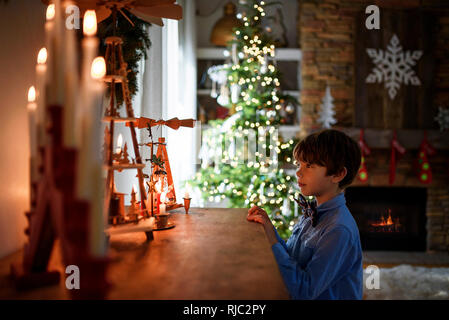 Ragazzo in piedi di fronte ad una credenza guardando le decorazioni di Natale Foto Stock
