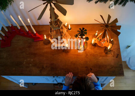 Ragazzo in piedi di fronte ad una credenza guardando le decorazioni di Natale Foto Stock