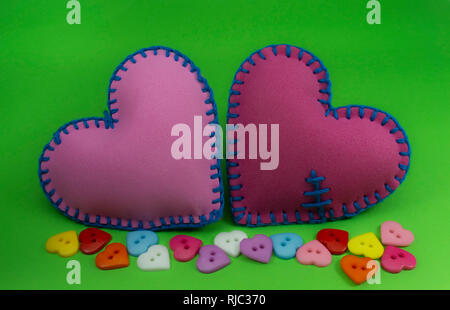 A forma di cuore cucito a mano cuori tessili realizzati in tessuto di colore rosa e cucita con fili blu sul verde Chroma Key per sfondo romantico San Valentino o con Foto Stock