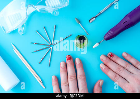 Strumenti per hardware professionale manicure e le mani delle donne con manicure su sfondo blu Foto Stock