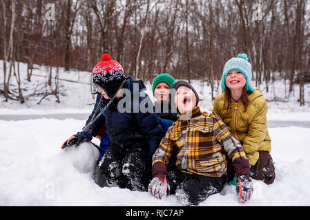 Quattro bambini seduti nella neve, Wisconsin, Stati Uniti Foto Stock