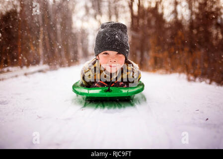 Ragazzo che giace su una slitta, Wisconsin, Stati Uniti Foto Stock