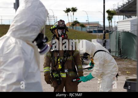 Il tenente José Alfaro del Miami-Dade Fire dipartimento HAZMAT team, detiene ancora mentre viene valutata da un equipaggio di decontaminazione durante una formazione congiunta esercizio ospitato dal Miami-Dade reparto antincendio e Homestead-Miami Speedway in Miami, Fla. gen. 11, 2018. Questo JTE focalizzata sulla creazione di capacità di risposta e la perfetta la transizione tra il primo locale i soccorritori e il follow-sul supporto fornito da La Guardia Nazionale e Active duty soldati. (Brevetto statunitense n. S. Esercito Foto Stock