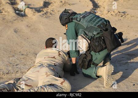 Una Guardia Civil spagnola membro della coalizione si cancella un soldato iracheno la M4 fucile durante un live esercitazione antincendio presso il Camp Besmaya, 7 gennaio 2018. Questa formazione fa parte del complesso di Combined Joint Task Force - Funzionamento inerenti risolvere la costruzione di capacità del partner di missione che si concentra sulla formazione e rafforzare la capacità di partnership forze che lottano ISIS. CJTF-funzione OIR è la coalizione globale per sconfiggere ISIS in Iraq e la Siria. Foto Stock