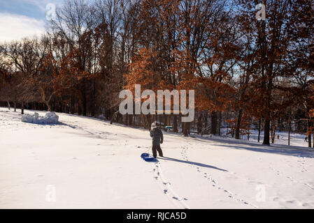 Ragazzo tirando una slitta nella neve, Wisconsin, Stati Uniti Foto Stock