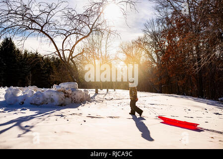 Ragazzo tirando una slitta nella neve, Wisconsin, Stati Uniti Foto Stock