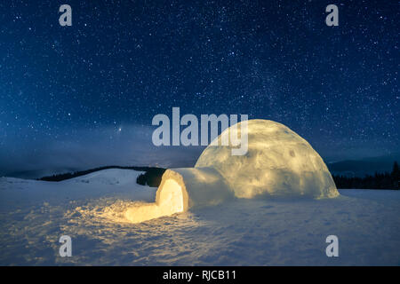 Fantastico paesaggio invernale incandescente da star light. Scena invernale con snowy igloo e la via lattea nel cielo notturno Foto Stock