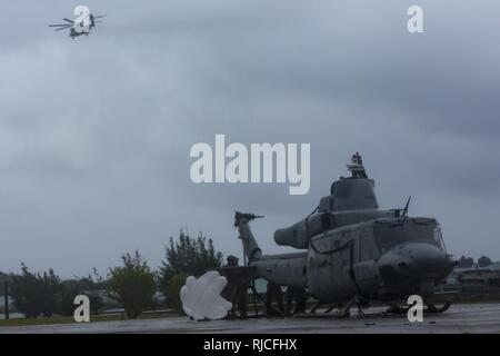 Un U.S. Marine CH-53E "Super Stallion" elicottero con il primo velivolo Marina Wing e la terza Marine Logistics Group, elicottero Supporto offload del team un UG-1Y "veleno" Huey elicottero dopo un atterraggio di emergenza a Uruma Beach, Base Navale spiaggia bianca, Okinawa, in Giappone. 8 gennaio 2018. La UH-1Y elicottero atterrato su Ikeijina una piccola isola a Okinawa principale dell'isola, dopo le indicazioni che il rotore principale è in movimento a pericolosamente ad alta velocità. Nessuno è stato ferito nell'incidente. Foto Stock