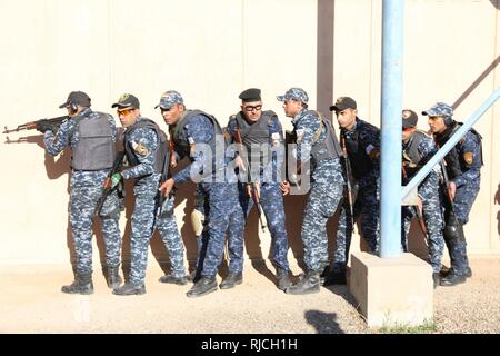 Iracheno di Polizia Federale formazione Accademia studenti stack su un ingresso a sparare house prima di ledere il loro bersaglio a Camp Dublin, Iraq, 10 gennaio, 2018. La formazione a costruire la capacità del partner sites è parte integrante della Combined Joint Task Force - Funzionamento inerenti risolvere la coalizione globale impegno di addestrare le forze di sicurezza irachene personale per sconfiggere ISIS. Foto Stock