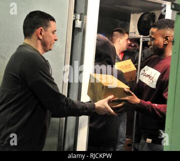 Sfc. Stephen Defritas (sinistra) e PFC. Johnnie Giddens contribuire a formare una linea di assemblaggio della decima divisione di montagna (LI) Supporto la brigata di soldati che lavorano insieme per riorganizzare la walk-in congelatori a Watertown dell'Esercito della Salvezza di giovedì, 11 gennaio. I soldati si sono offerti volontariamente nella comunità in onore del National Dr Martin Luther King Jr. vacanza. Foto Stock