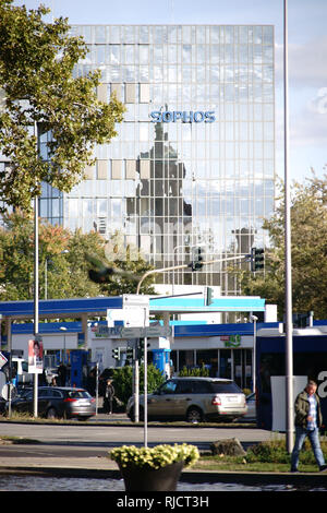 Wiesbaden, Germania - 25 Settembre 2018: il traffico in corrispondenza di una stazione di gas e i pedoni di fronte al grattacielo moderno ed edificio per uffici di Sophos su S Foto Stock