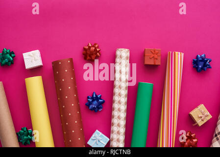 Vesti il tuo regalo con un luminoso e bello regalo carta di avvolgimento. Rotoli di bright carta di avvolgimento su sfondo rosa. Foto Stock