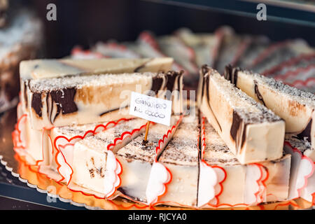Primo piano della noce di cocco cioccolato formaggio cremoso cheesecake swirl fette dessert sul vassoio la finestra di visualizzazione in pasticceria gourmet cafè italiano con segno Foto Stock