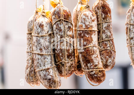 Primo piano di rulli di salame salsicce appeso sulla stringa sul display in un mercato negozio di macellaio gruppo di sfondo nel mercato in Firenze, Italia Foto Stock