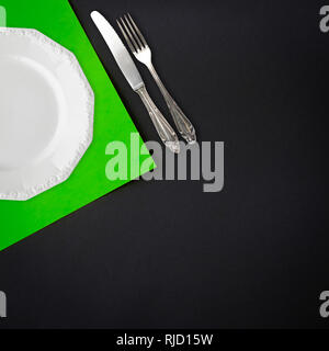 Piastra e coltello e forchetta su sfondo nero tabella laici piatta Foto Stock