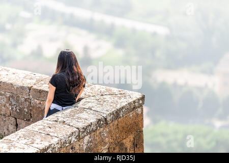 Orvieto, Italia - 3 Settembre 2018: piccola e antica città medievale borgo in Umbria con le mura della città fortezza fort tower e asiatica di giovane donna in piedi Foto Stock