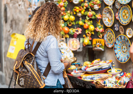 Orvieto, Italia - 3 Settembre 2018: Una donna shopping per souvenir nella piccola città italiana città da venditore ambulante tenendo la piastra al display di vendita al dettaglio Foto Stock