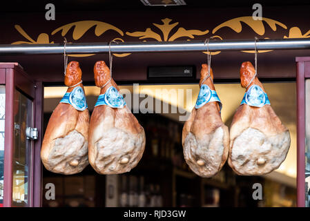 Roma, Italia - 4 Settembre 2018: primo piano del prosciutto di Parma Prosciutto appeso sulla stringa sul display in un mercato butcher shop store sullo sfondo di ingresso Foto Stock