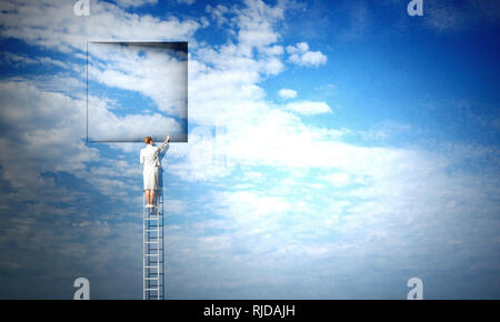 Imprenditrice permanente sulla scaletta e salendo fino alla finestra. I supporti misti Foto Stock