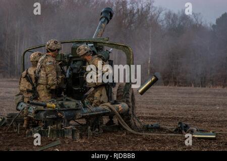 Artiglieri dalla batteria B, 3° Battaglione, campo 320reggimento di artiglieria, 101st Divisione Aerotrasportata brigata di artiglieria, 101st Airborne Division (Air Assault), il fuoco di un M119A3 Obice durante la certificazione di plotone, 24 Gennaio a Fort Campbell, Kentucky. L'obici imbracatura sono stati caricati nel luogo da tre UH-60 Black Hawk elicotteri. Foto Stock