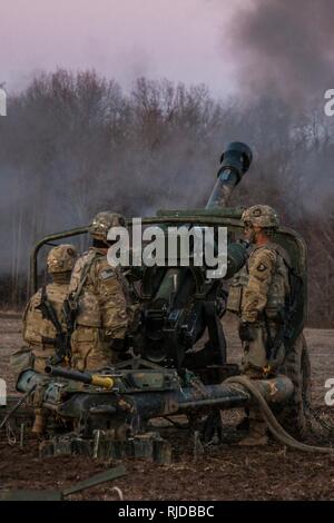 Artiglieri dalla batteria B, 3° Battaglione, campo 320reggimento di artiglieria, 101st Divisione Aerotrasportata brigata di artiglieria, 101st Airborne Division (Air Assault), il fuoco di un M119A3 Obice durante la certificazione di plotone, 24 Gennaio a Fort Campbell, Kentucky. L'obici imbracatura sono stati caricati nel luogo da tre UH-60 Black Hawk elicotteri. Foto Stock