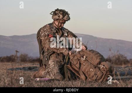 Un jumpmaster dal 173rd Airborne Brigade ispeziona il suo equipaggiamento immediatamente dopo lo sbarco sulla zona di caduta nel nord Italia. Foto Stock