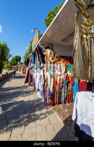 Mercato sulle rive del Nilo dal Tempio di Kom Ombo, Alto Egitto la vendita tradizionale galabeyas colorati come souvenir per i turisti provenienti da crociere Foto Stock