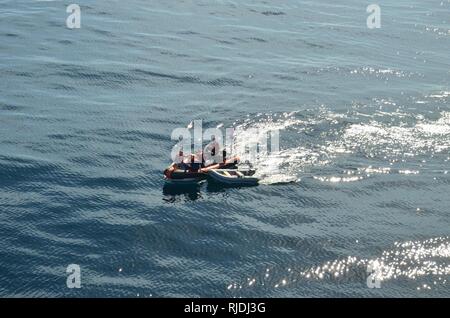 Il suo equipaggio dalla Guardacoste Ippoglossi (WPB-87340), assistere un uomo che ha abbandonato la sua barca a vela a causa di un incendio su una piccola barca in San Pedro canale vicino San Pedro, California, 23 gennaio, 2018. Gli equipaggi dall'halibut, Coast Guard Avanti Base Operativa Point Mugu, Stazione della Guardia Costiera Los Angeles-Long Beach e ad altre agenzie locali hanno risposto al fuoco in barca a San Pedro canale. Foto Stock