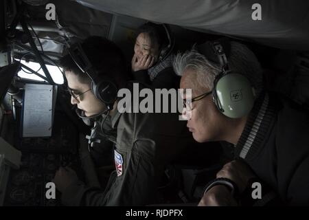 Stati Uniti Air Force Staff Sgt. Possibilità Italiano, 909th Air Refuelling Squadron KC-135 Stratotanker boom operatore, Kazumi Kaneshiro, Presidente di Lions Club e Noriyasu Shimabukuro, Vice Presidente Okinawa della Camera di Commercio e Industria di condurre un comandante onorario volo di orientamento 11 gennaio 2018 sull'Oceano Pacifico. Il volo enhanced leader civili' comprensione di Kadena's operazioni con esperienza di prima mano di air-air refuelling e incontro con 909th ARS leader. Foto Stock